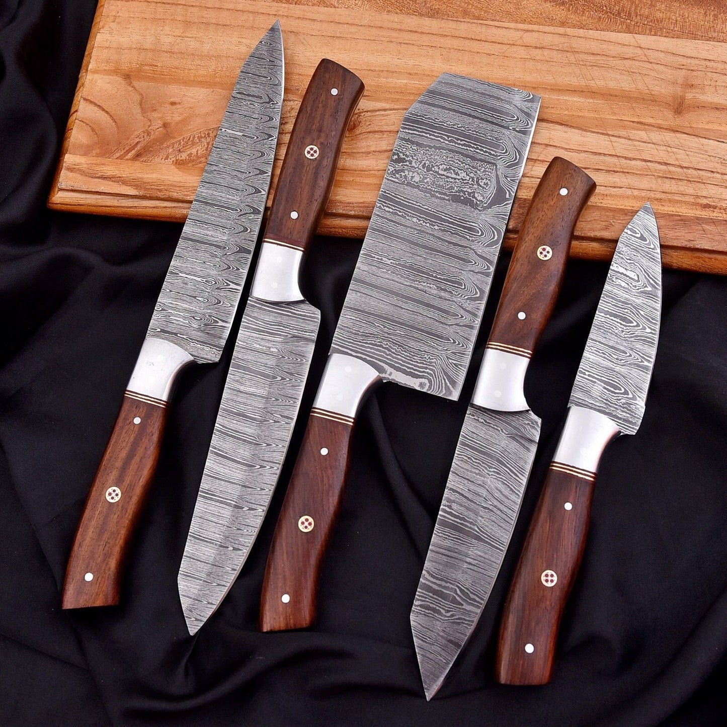 Hand forged 5 pc Damascus steel culinary knife set arranged on a natural wood surface, highlighting professional balance and edge quality