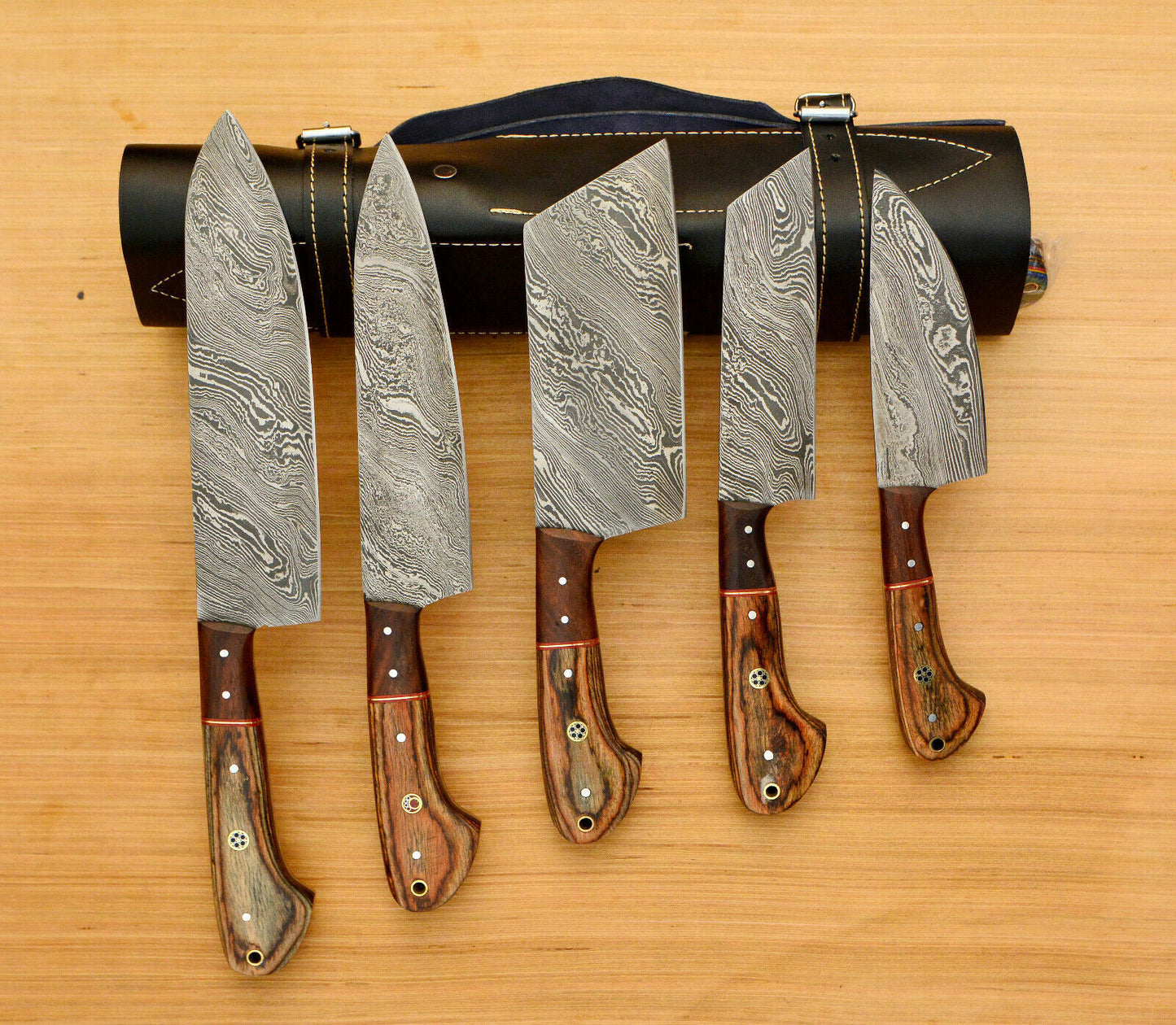 Handmade 5 piece Damascus steel chef knife set neatly organized in a professional hand tooled leather roll.