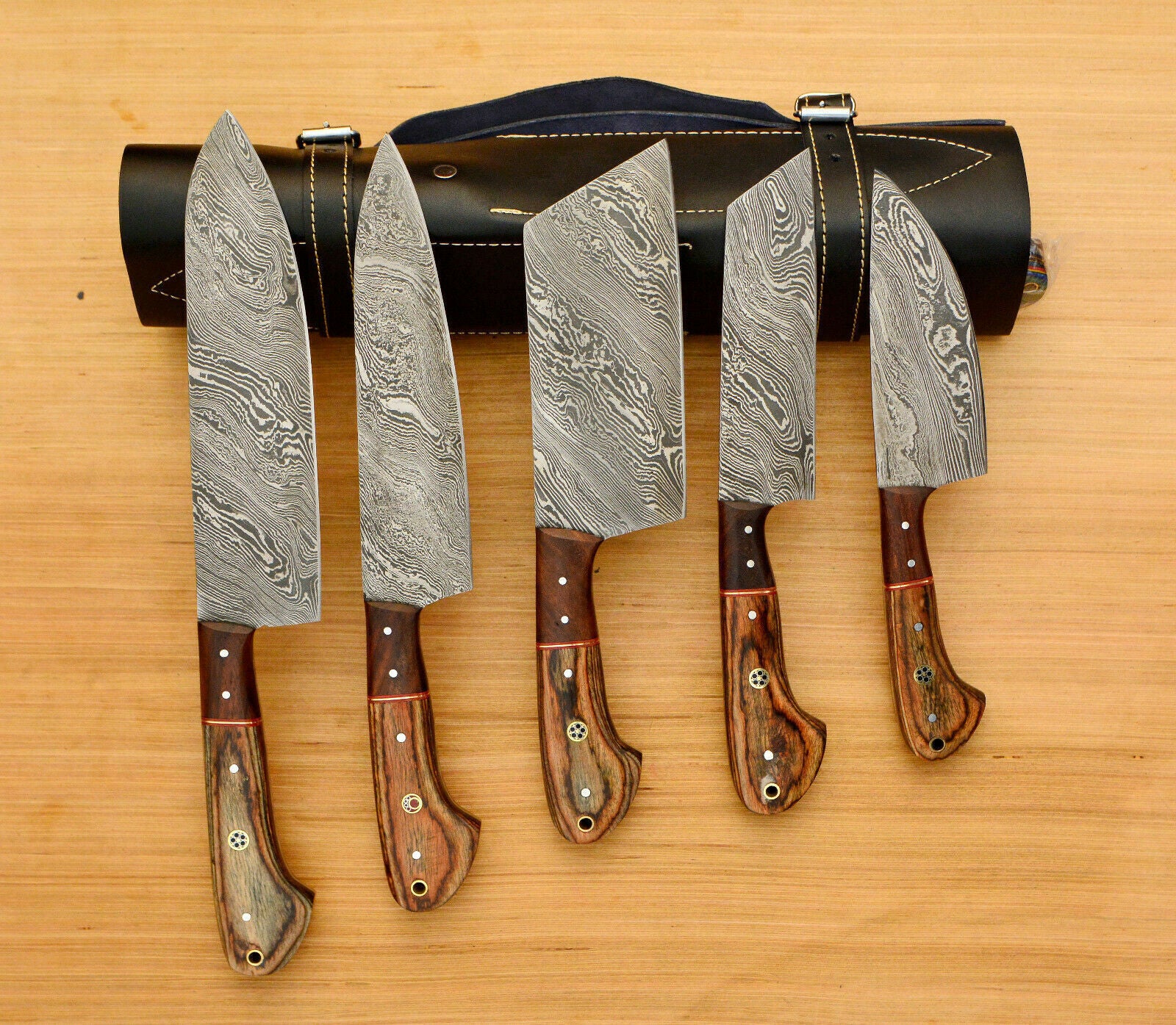 Handmade 5 piece Damascus steel chef knife set neatly organized in a professional hand tooled leather roll.