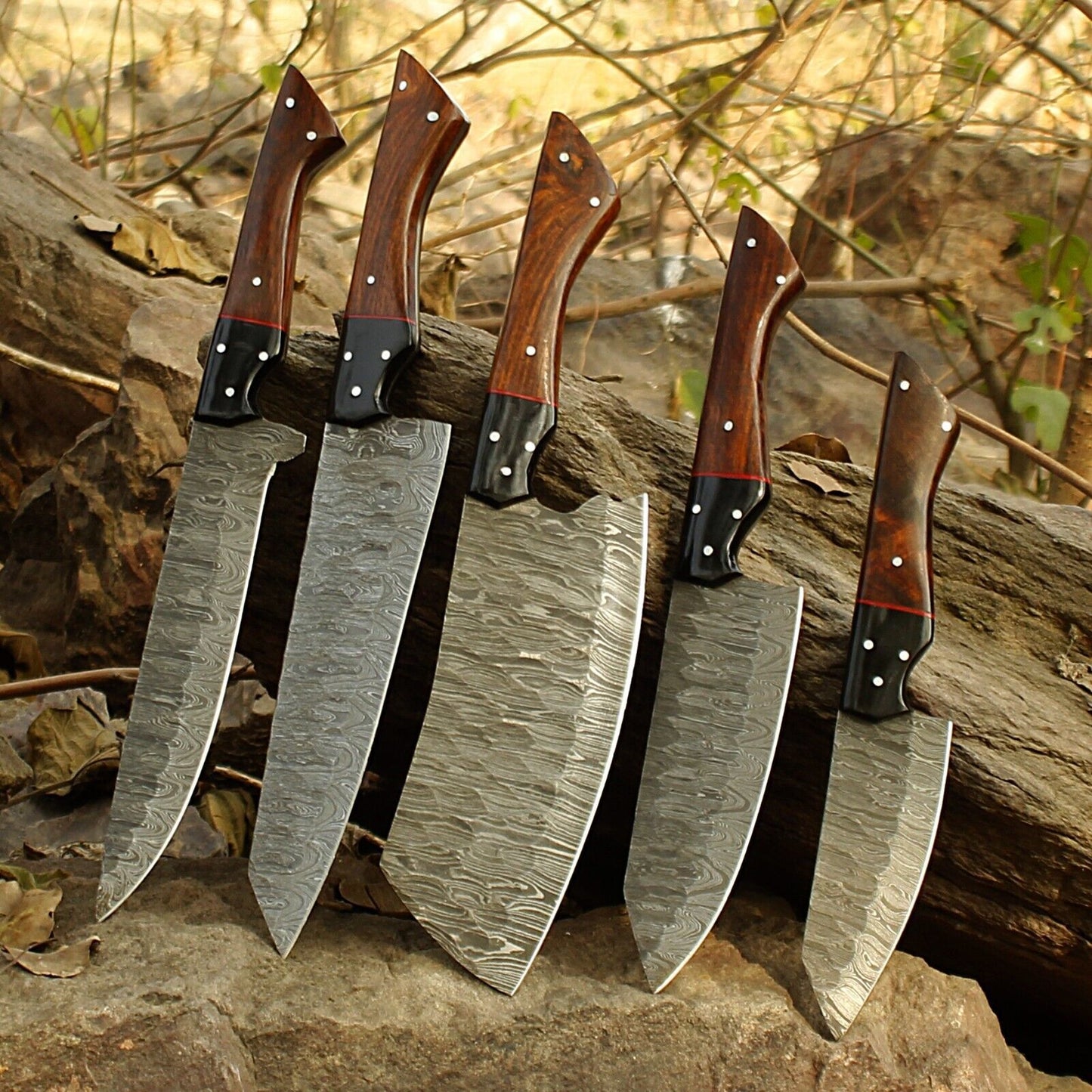 Top down view of a 5pc Damascus steel kitchen knife set highlighting the hand ground edges and custom craftsmanship.