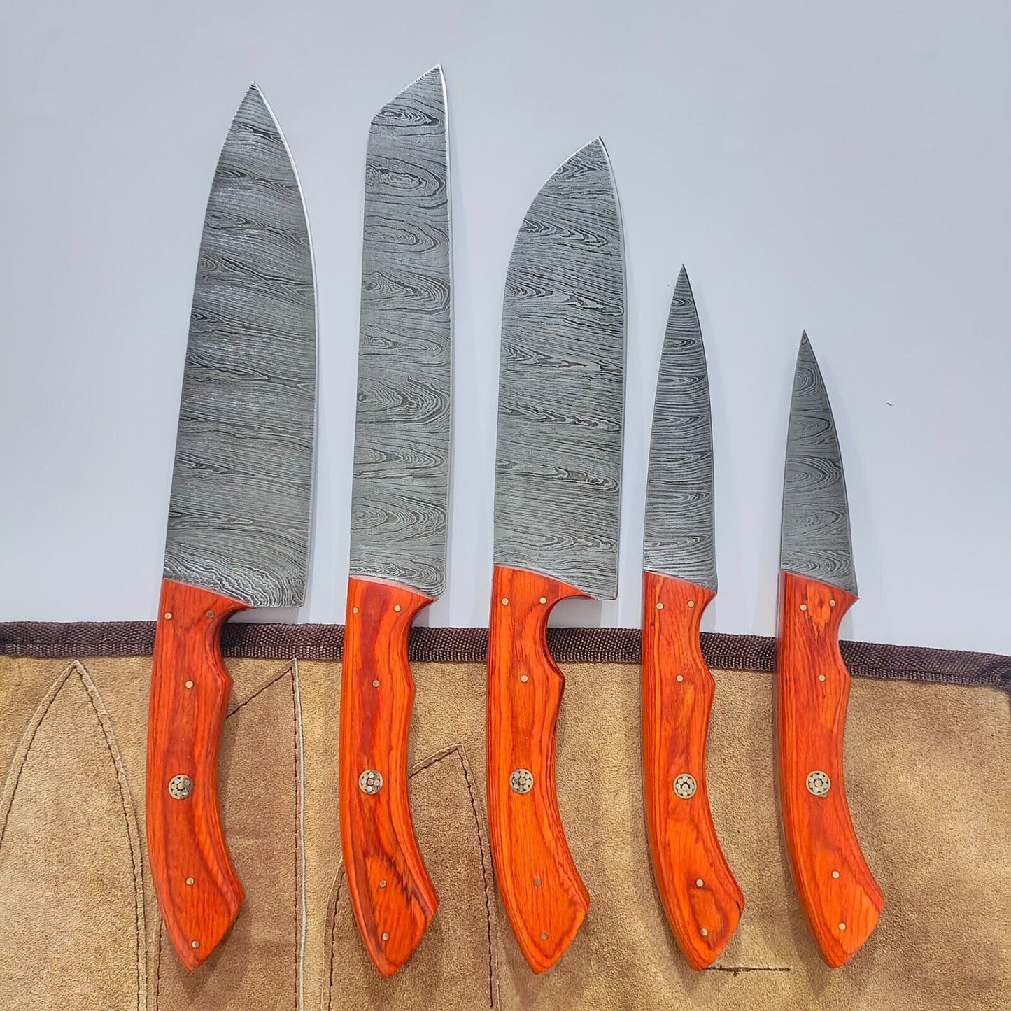 Hand forged 5 piece Damascus steel chef knife set featuring vibrant Pukka Wood handles and durable steel bolsters.