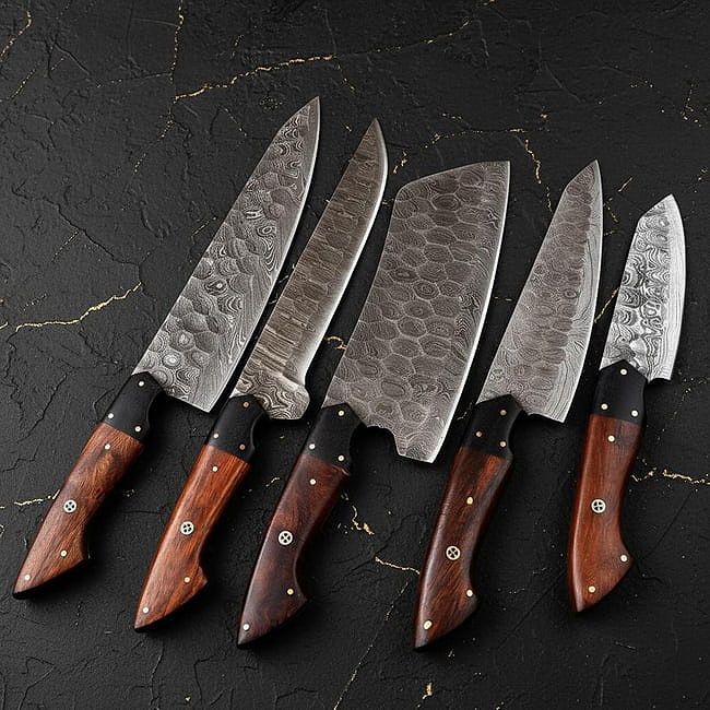 5pc handmade Damascus steel chef knife set with leather roll bag displayed on rustic wood surface.